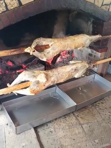 Whole lamb spit-roasting over open fire in Bulgarian stone oven