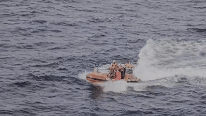 Orange inflatable boat speeds through choppy waters with passengers