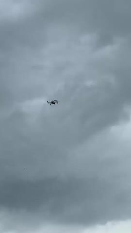 The video shows a drone flying in a cloudy sky. The drone appears to be a quadcopter, with four propellers. The sky is overcast and gray. There are no people visible in the video.