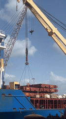 Crane lifts metal cargo from blue ship deck