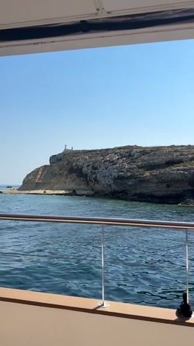 Boat ride across calm ocean waters past a rocky island