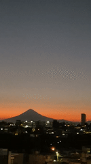 Twilight cityscape captured in Puebla with Popocatépetl volcano backdrop