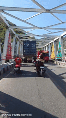 Traffic flows across a white truss bridge in Gorontalo