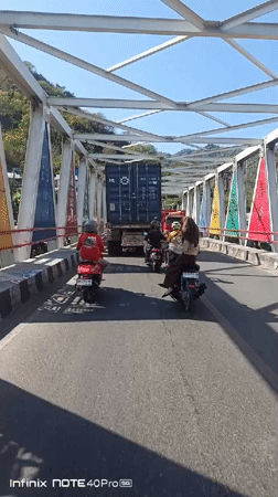 Traffic flows across a white truss bridge in Gorontalo