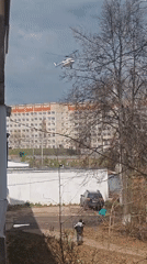 White helicopter spotted over urban area amid bare trees