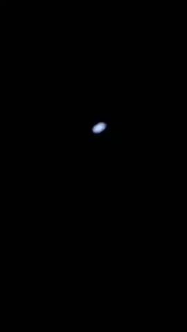 The video is a very dark screen with a tiny, bright white light in the center. The light appears to be a celestial body, possibly the moon or a planet, viewed from a distance. The light does not move significantly throughout the short clip.