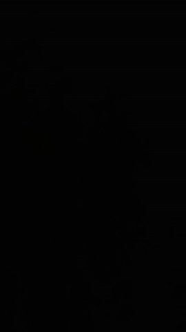 The video is mostly black, but at 00:01, a brief, blurry image appears. It shows a person with a dark complexion and dark hair, wearing dark clothing. They are facing forward and smiling. The background is obscured by darkness.