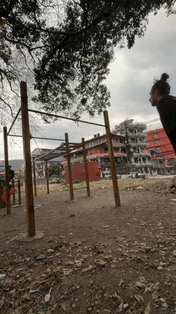 Man performs somersault over pull-up bar in Pokhara park