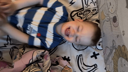 Toddler in striped shirt rests on bed in Rusanovo
