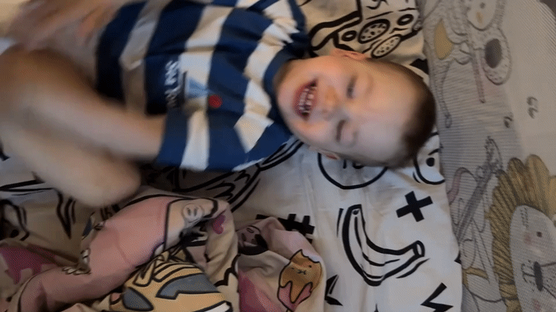 Toddler in striped shirt rests on bed in Rusanovo