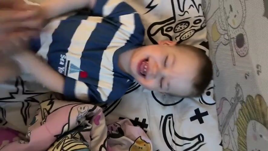 Toddler in striped shirt rests on bed in Rusanovo