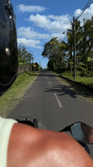 Motorcycle rider travels past two men on Indonesian road