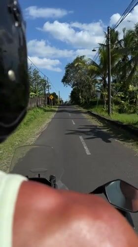 Motorcycle rider travels past two men on Indonesian road