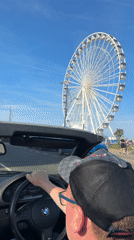 Convertible driver passes Great Yarmouth Ferris wheel on sunny day