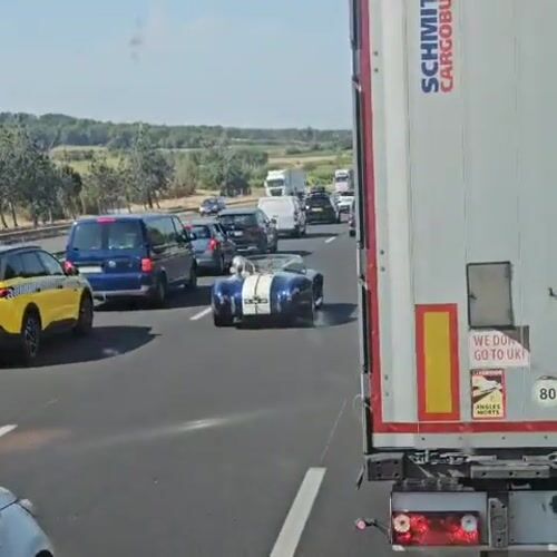 Blue convertible with racing stripes cruises French highway traffic