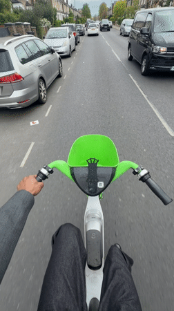 Rider uses Lime e-scooter on London residential street