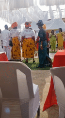 Outdoor event features speaker, traditional African dress, colorful decorations