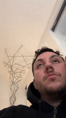 Man examines art, handles paper models in London room