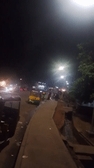 Nighttime street scene captures trucks, vendors, plastic waste operations