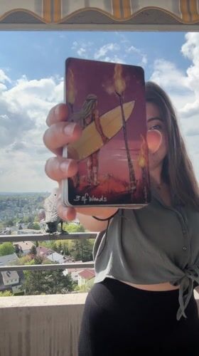 Woman displays tarot card on balcony in Waiblingen