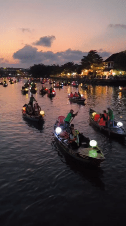 Tourists explore illuminated Hoi An waterfront and ancient town streets