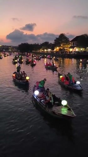 Tourists explore illuminated Hoi An waterfront and ancient town streets