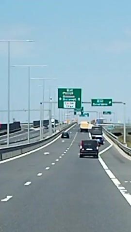 The video shows a highway with several cars and trucks. There are green signs indicating directions to various locations, including Bucharest and Constanța. The weather appears to be clear and sunny. The camera is mounted on a vehicle moving along the highway.