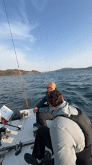 Three men sail in Vladivostok bay during morning hours