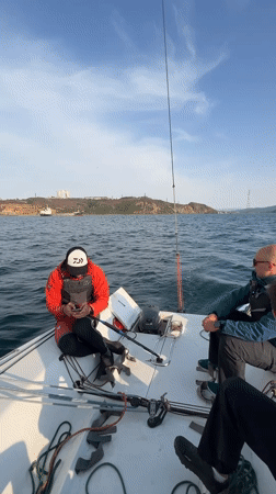 Three men sail in Vladivostok bay during morning hours