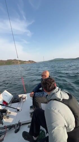 Three men sail in Vladivostok bay during morning hours
