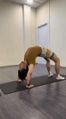 Person performs yoga bridge pose in light green room