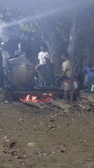 Late-night outdoor gathering around a wood-fired pot