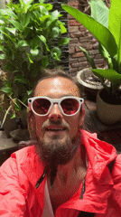 Smiling portrait in red jacket and pink-lens sunglasses