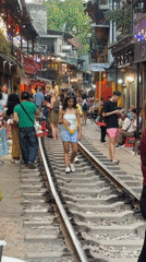 Pedestrians walk along railway tracks through Hanoi street