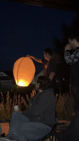 Sky lantern release over a residential neighborhood at night