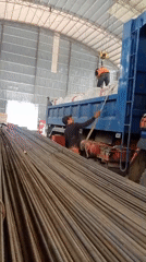 Workers securing a load on a blue dump truck in Malaysia