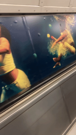 London display case shows underwater performers juggling colored balls