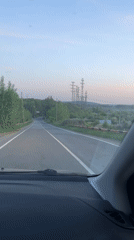 Vehicle travels tree-lined road in Chaikovsky, Russia