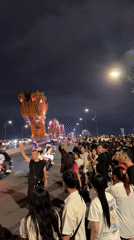 Nighttime crowd gathers near illuminated Dragon Bridge in Da Nang