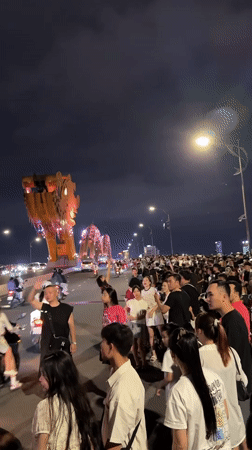 Nighttime crowd gathers near illuminated Dragon Bridge in Da Nang