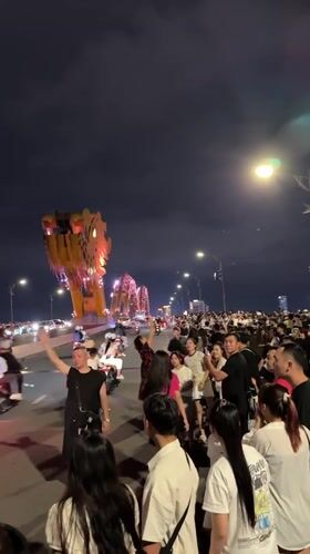 Nighttime crowd gathers near illuminated Dragon Bridge in Da Nang