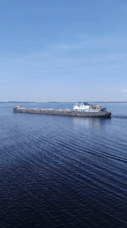 Cargo barge transits Russian waterway near Sheksna under clear skies