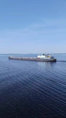 Cargo barge transits Russian waterway near Sheksna under clear skies
