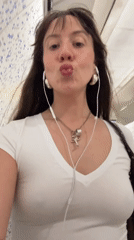 Woman with dark hair photographed wearing white shirt and jewelry