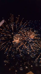 Fireworks display over a fairground draws a crowd at night