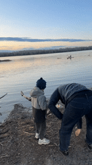 Man cleans waterfront trash with child in Zheleznogorsk