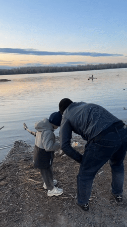 Man cleans waterfront trash with child in Zheleznogorsk