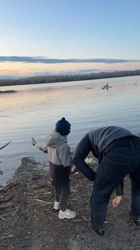 Man cleans waterfront trash with child in Zheleznogorsk