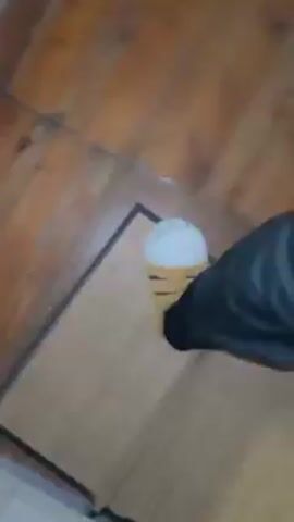 The video shows a person wearing black pants and light-colored slippers with white tips standing on a brown mat on a wooden floor. The person pivots their feet on the mat. The camera angle is from the person's point of view.