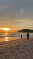 Sunset watchers gather at Thailand beach during golden hour